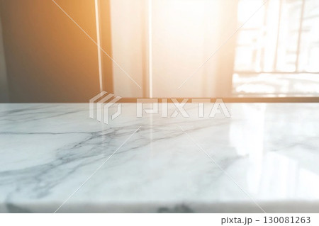 White marble tabletop with sunlight illuminating a minimalistic indoor space 130081263