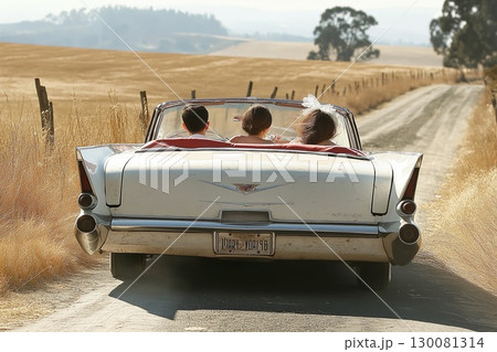 Couple enjoying a drive in a classic car on a serene country road in the 1950s 130081314