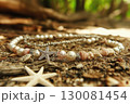 Elegant seashell bracelet adorned with pearls and coral fragments on a sandy beach 130081454