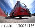 Bright red bus parked under a blue sky with wispy clouds at a roadside location 130081456