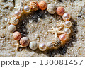 Elegant bracelet made of pearls and seashells resting on a sandy beach in sunlight 130081457
