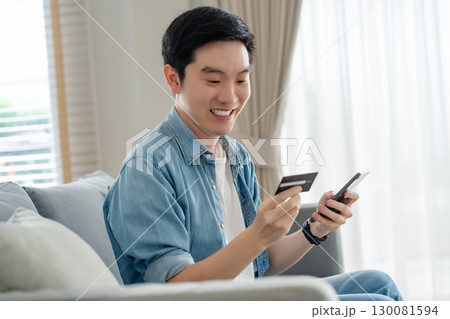 Young asian man sitting on sofa in living room 130081594
