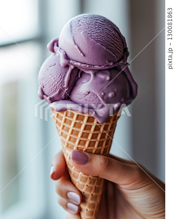 Hand holding triple scoop ube ice cream in waffle cone with melting texture by the window. Tasty summer dessert. Hand holding triple scoop ube ice cream in waffle cone with melting texture by the window. Tasty summer dessert. 130081863