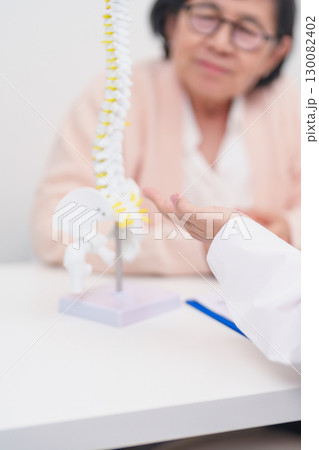 Elderly Patient consulting Doctor with Spine anatomy for Spinal Cord Disorder and disease, Back pain, Lumbar, Sacral pelvis, Cervical neck, Thoracic, Coccyx, Orthopedist, chiropractic, Office Syndrome 130082402