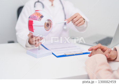 Elderly Patient consulting Doctor to Eye disease, Senior Medical Diagnosis. Anatomy Eye model for Cataract, Glaucoma, Age Related Macular Degeneration, Diabetic Retinopathy, Vitreous, health concept 130082459