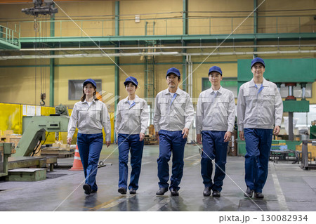 工場の中を並んで歩く作業員グループ 130082934