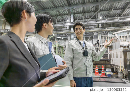 工場を視察する女性ビジネスパーソンと男性作業員 130083332