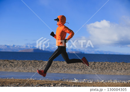 Woman runner training at winter lakeside 130084305