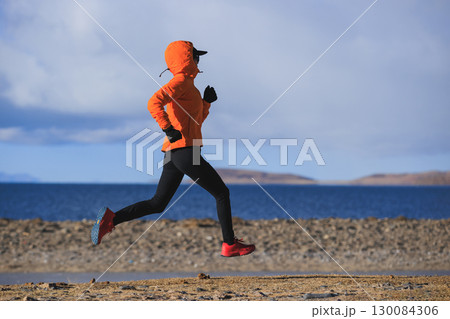 Woman runner training at winter lakeside Woman runner training at winter lakeside 130084306