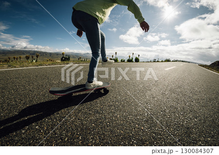 Skateboarder skateboarding on the mountain road Skateboarder skateboarding on the mountain road 130084307