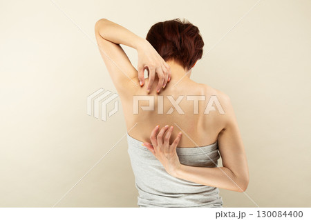 背中を掻くアジア人の若い女性. 130084400