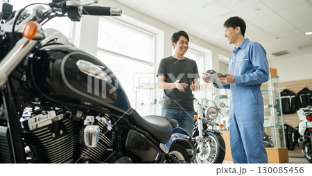 バイクショップで商談をする客と店員 130085456