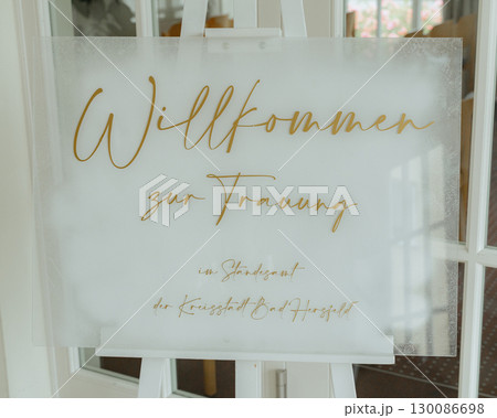 Elegant welcome sign for a wedding displayed on an easel at the venue entrance. Gold cursive writing adds a touch of sophistication, welcoming guests to the special event 130086698