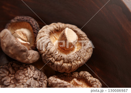 Dried edible shiitake mushrooms in a rustic wooden bowl.  130086987