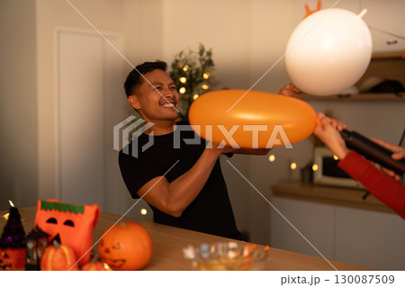 Halloween Playfulness. Man and woman having fun with balloons in festive setting. Halloween Playfulness. Man and woman having fun with balloons in festive setting. 130087509