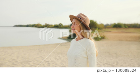 Happy woman on beach, wear hat standing on sea coast background 130088324