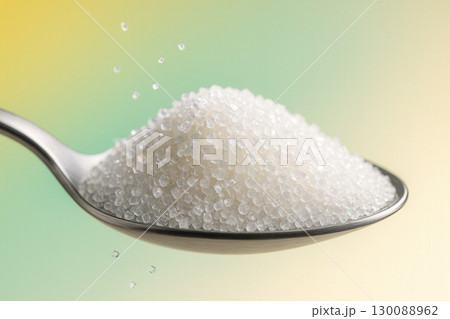 Granulated Sugar Crystals Heaped On Metal Spoon With Falling Grains 130088962