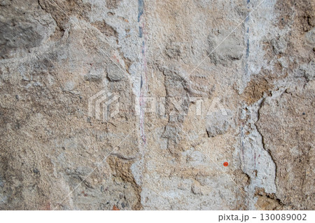 Gray structural stone wall of the ancient building consists of old structural plaster. 130089002