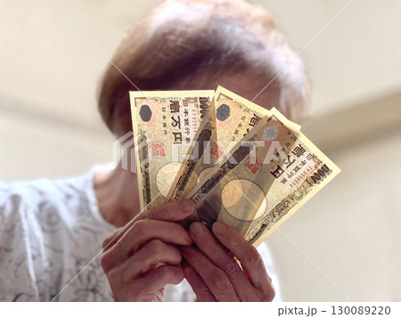 顔の前で3万円を持つ高齢女性 130089220