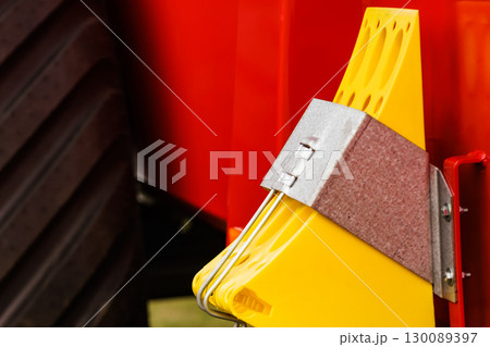 Yellow brake stop blocks wedges on red tractor 130089397