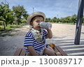 公園でベンチに座って水を飲む幼児 130089717