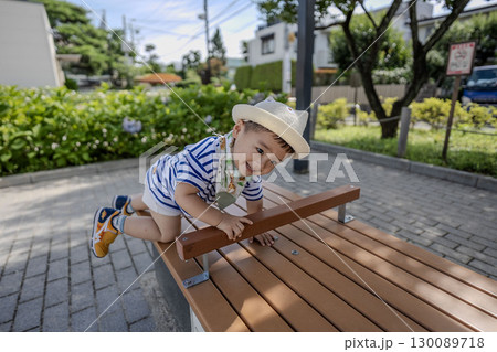 公園のベンチに登ろうとする子供 130089718