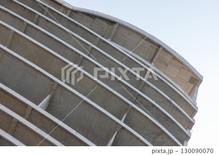 Concrete building under construction is under bright sky, abstract architectural photo 130090070