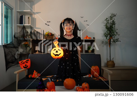 Halloween Joy. Young girl holding a glowing pumpkin lantern, celebrating Halloween spirit. Halloween Joy. Young girl holding a glowing pumpkin lantern, celebrating Halloween spirit. 130091606