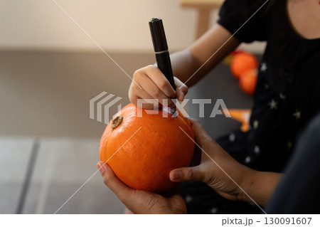 Pumpkin Carving. Child drawing on a pumpkin with a marker during Halloween. Pumpkin Carving. Child drawing on a pumpkin with a marker during Halloween. 130091607