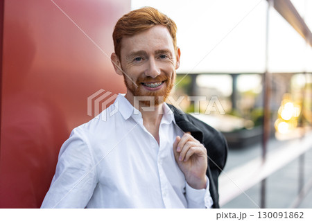 Ginger bearded man in white shirt and formal trousers posing outdoors 130091862