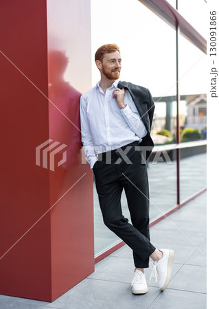Young adult ginger-haired man with beard wearing white shirt and black trousers 130091866
