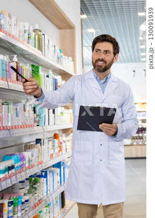 Bearded male pharmacist showing medicine on the shelf in the pharmacy 130091939