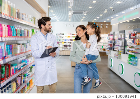 Young mom with a cute kid talking to a pharmacist at the chemists Young mom with a cute kid talking to a pharmacist at the chemists 130091941