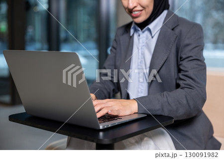 Muslim businesswoman in hijab working on laptop and looking involved 130091982
