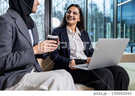Two women sitting together, talking and looking involved and excited 130092043