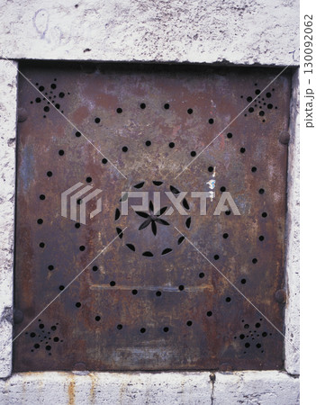 ローマ市内の古い町並み アパートの壁にはめ込まれている錆びついた幾何学模様の鉄板 130092062