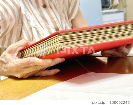 分厚いアルバムを持つ高齢女性の手元 130092246