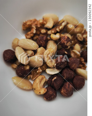 Mixed nuts filling a white bowl, healthy snack or ingredient for autumn recipes 130092342