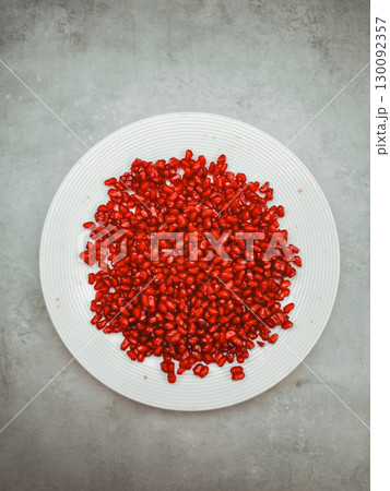 Pomegranate seeds filling white plate on gray background representing rosh hashanah and rebirth 130092357