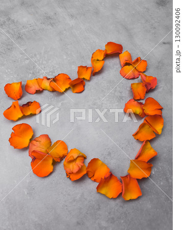 Orange rose petals forming heart shape on gray background 130092406