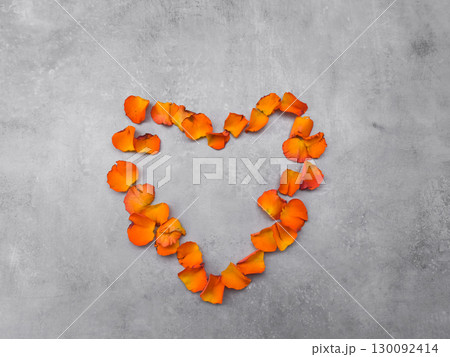 Orange rose petals forming heart shape on gray background 130092414