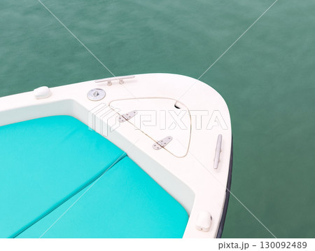 Bow of white motorboat with turquoise cushions floating on calm water Bow of white motorboat with turquoise cushions floating on calm water 130092489