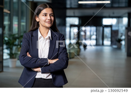 Cute young woman in jacket and white shirt standing with her arms crossed 130092549