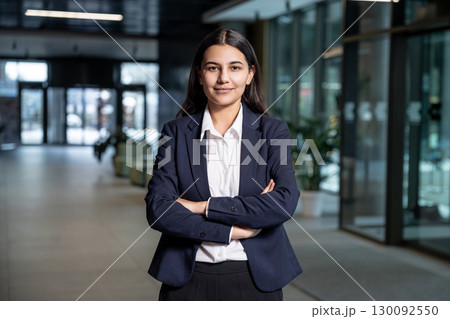 Cute young woman in jacket and white shirt standing with her arms crossed Cute young woman in jacket and white shirt standing with her arms crossed 130092550