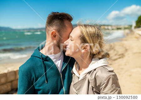 Couple sharing passionate kiss on sandy beach shore with waves in background Couple sharing passionate kiss on sandy beach shore with waves in background 130092580