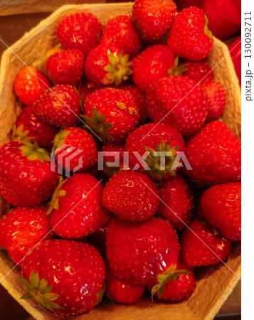 Fresh red strawberries overflowing a cardboard container 130092711