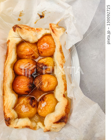 Delicious apricot tart emerging from baking paper on marble surface Delicious apricot tart emerging from baking paper on marble surface 130092725