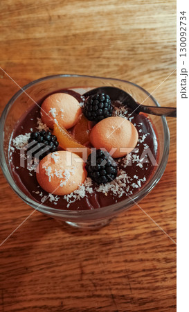 Delicious chocolate pudding with biscuits, blackberries and candied orange zest on wooden table strbske pleso, high tatras 130092734