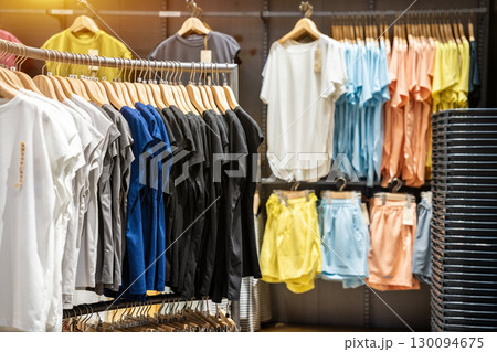 Row of colorful cotton coat suits are hanged by wooden cloth hanger on the rail. Fashion lifestyle object, close-up and selective focus. 130094675