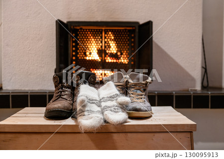 Winter boots and wool mittens drying in front of fireplace indoors cozy home Winter boots and wool mittens drying in front of fireplace indoors cozy home 130095913